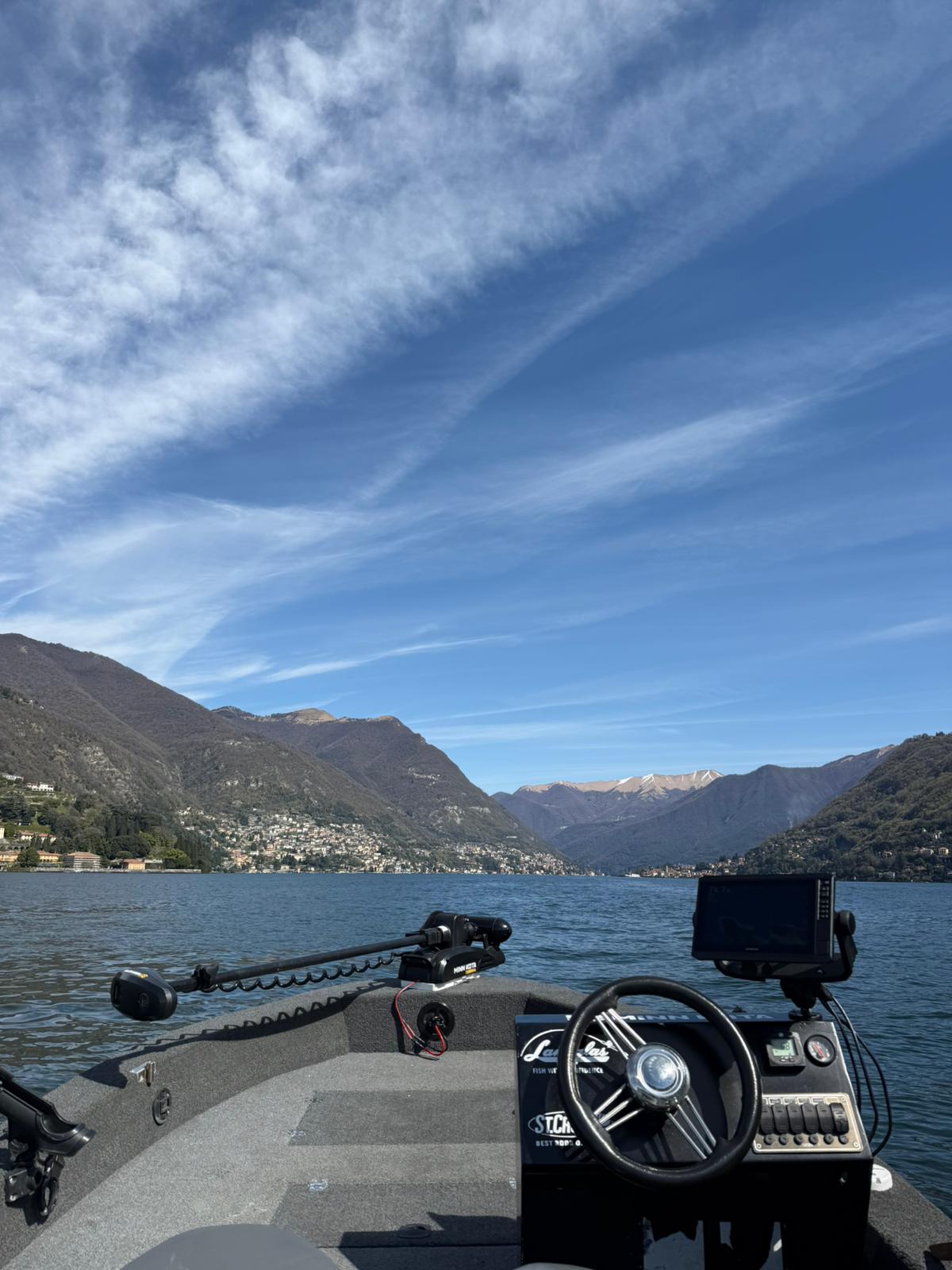 Boat on a lake with mountains in the background under a blue sky.